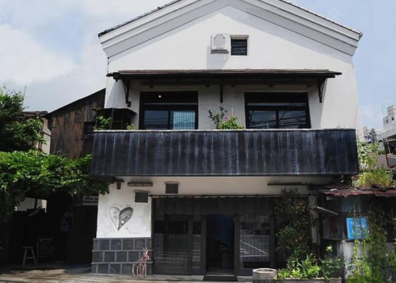 OKURA's kura-style storehouse shopfront in Daikanyama: white plaster gable, dark timber, plants, no people