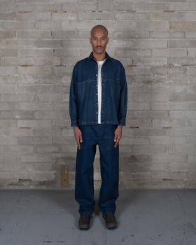 A man wearing an indigo-dyed Olderbrother denim overshirt and matching wide-leg jeans