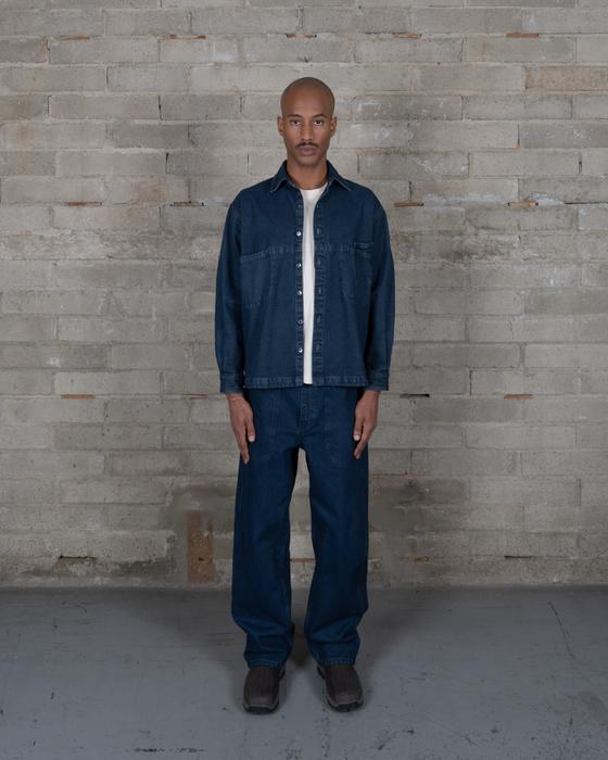 A man wearing an indigo-dyed Olderbrother denim overshirt and matching wide-leg jeans