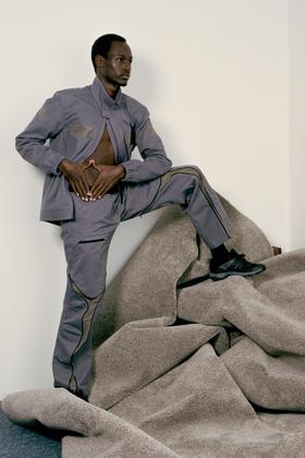 A man wearing a grey Olly Shinder technical jacket and matching curved-seam trousers