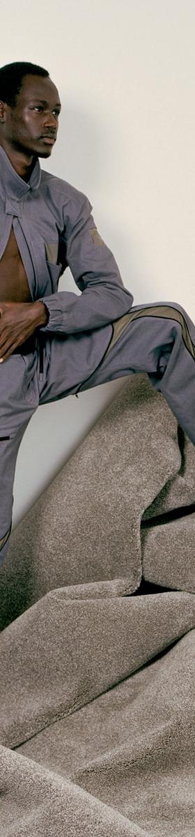 A man wearing a grey Olly Shinder technical jacket and matching curved-seam trousers