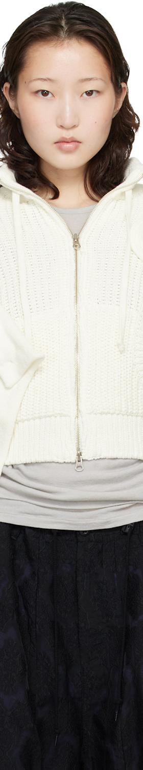 A woman wearing an off-white OPEN YY rosette-appliqué zip-up knit cardigan with a black skirt