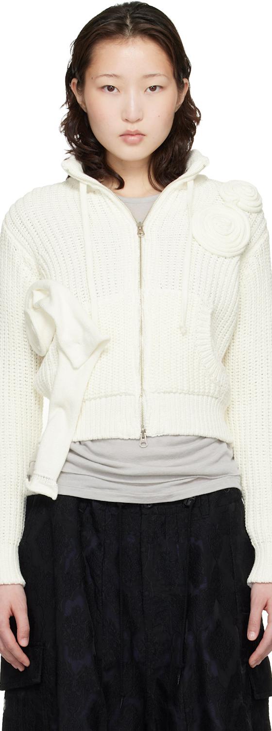 A woman wearing an off-white OPEN YY rosette-appliqué zip-up knit cardigan with a black skirt
