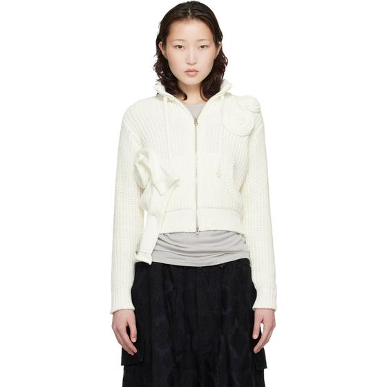 A woman wearing an off-white OPEN YY rosette-appliqué zip-up knit cardigan with a black skirt
