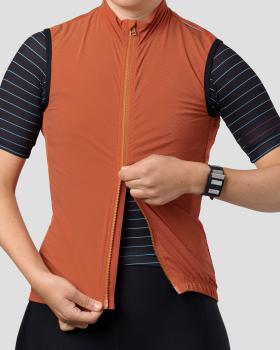 A cyclist wearing a rust orange Ornot wind vest over a navy striped jersey