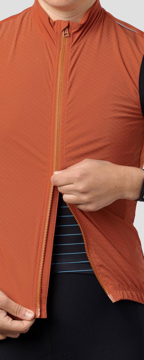A cyclist wearing a rust orange Ornot wind vest over a navy striped jersey
