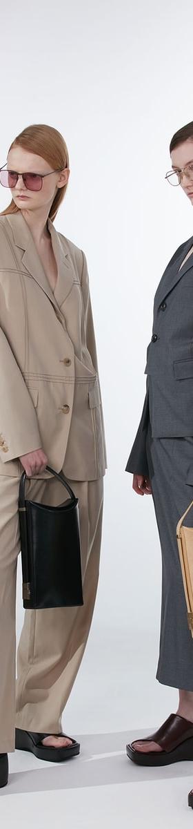 Two models in oversized tailoring holding black and tan OSOI leather bags