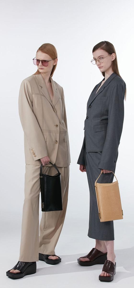 Two models in oversized tailoring holding black and tan OSOI leather bags