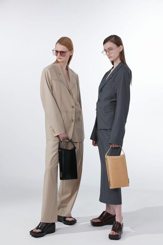 Two models in oversized tailoring holding black and tan OSOI leather bags