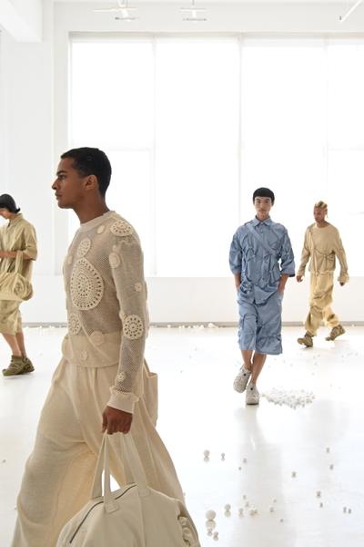Models walking in a bright studio wearing textured knitwear, oversized trousers and sneakers