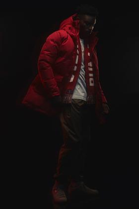 A man wearing a red Outlaw Moscow puffer parka with a striped scarf