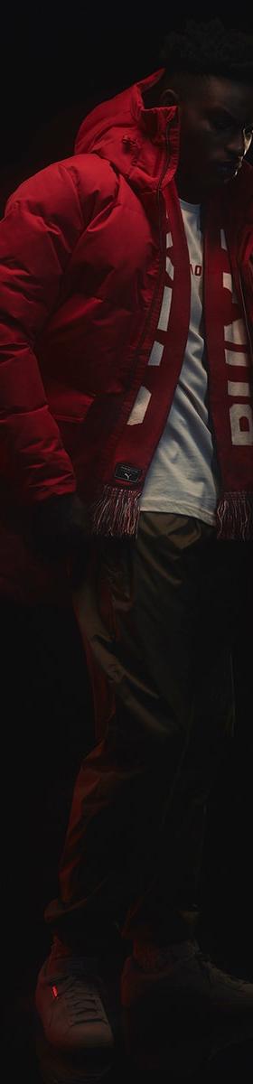 A man wearing a red Outlaw Moscow puffer parka with a striped scarf