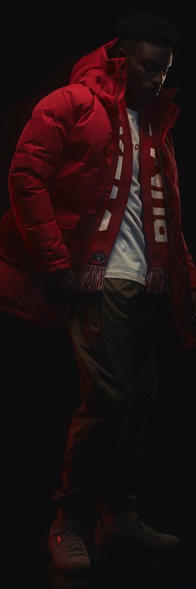 A man wearing a red Outlaw Moscow puffer parka with a striped scarf