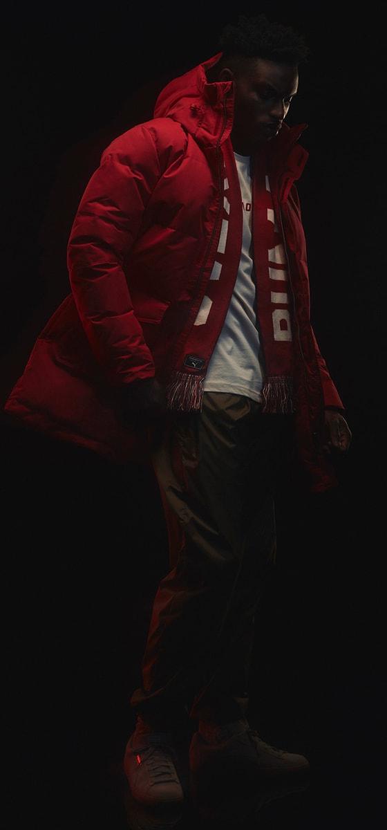 A man wearing a red Outlaw Moscow puffer parka with a striped scarf
