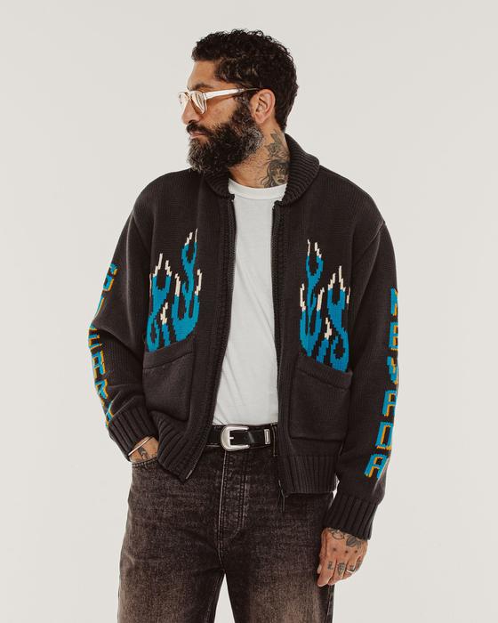 A man wearing a charcoal P&Co Valley intarsia zip knit with blue flame sleeves