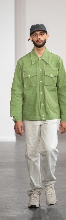 A man wearing a green Paa chore jacket with white trousers