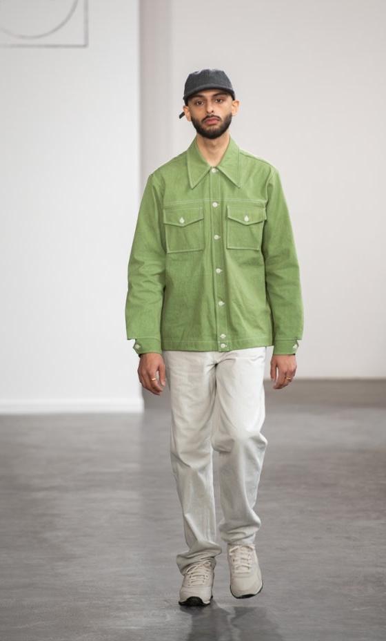A man wearing a green Paa chore jacket with white trousers