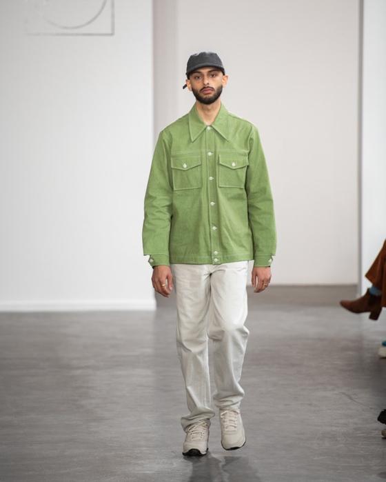 A man wearing a green Paa chore jacket with white trousers