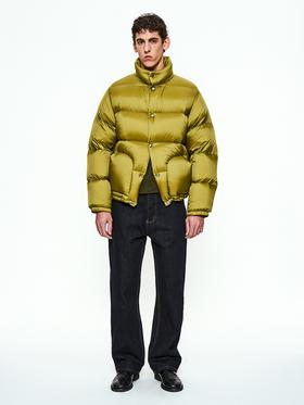 A man wearing a chartreuse PARTIMENTO puffer jacket with dark denim jeans