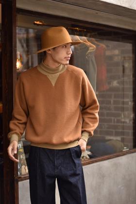 A man wearing a camel loopwheel Pherrow's sweatshirt with a felt hat and indigo denim trousers