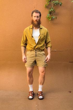 A man wearing a mustard PHIPPS overshirt with khaki corduroy button-fly shorts