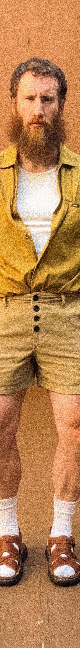 A man wearing a mustard PHIPPS overshirt with khaki corduroy button-fly shorts