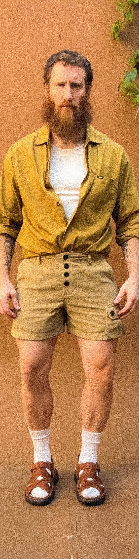 A man wearing a mustard PHIPPS overshirt with khaki corduroy button-fly shorts