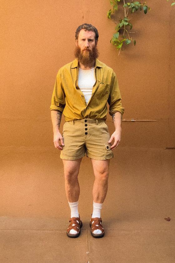 A man wearing a mustard PHIPPS overshirt with khaki corduroy button-fly shorts