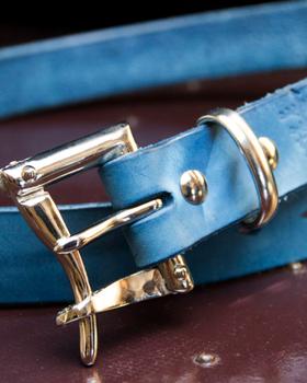 An indigo-dyed leather belt with a polished double-prong buckle