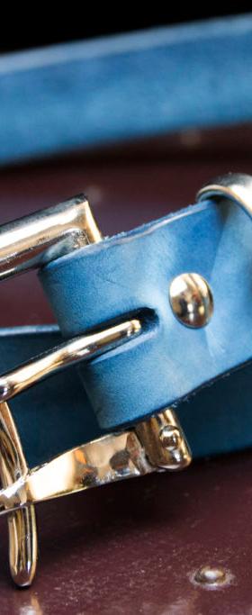 An indigo-dyed leather belt with a polished double-prong buckle