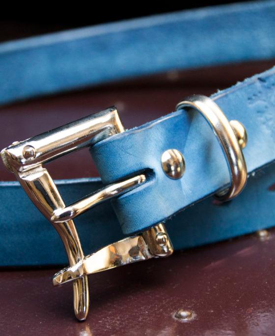 An indigo-dyed leather belt with a polished double-prong buckle