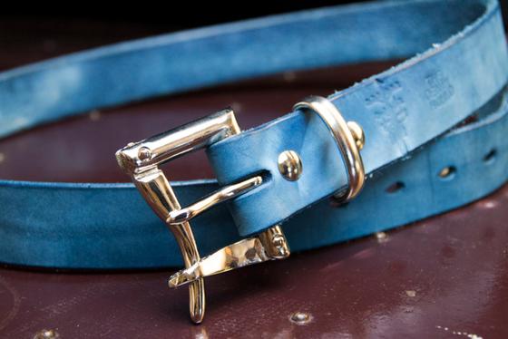 An indigo-dyed leather belt with a polished double-prong buckle