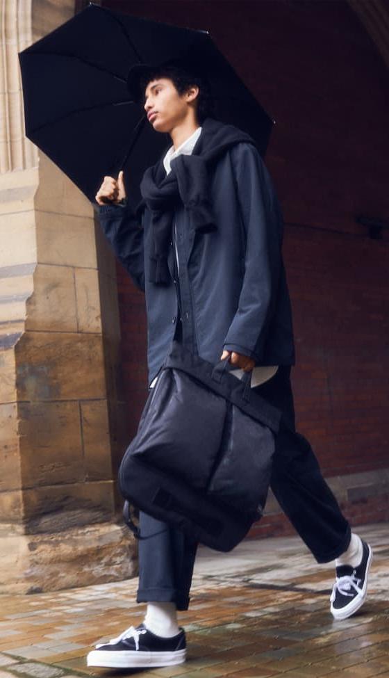 A man in a navy hooded coat carrying a black PORTER-YOSHIDA & CO. nylon tote bag
