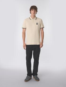 A man wearing a cream tipped Pretty Green polo shirt with black trousers