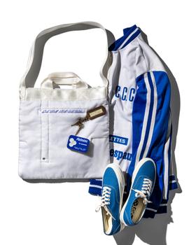 A white quilted Puebco tote bag styled with a blue track jacket and sneakers