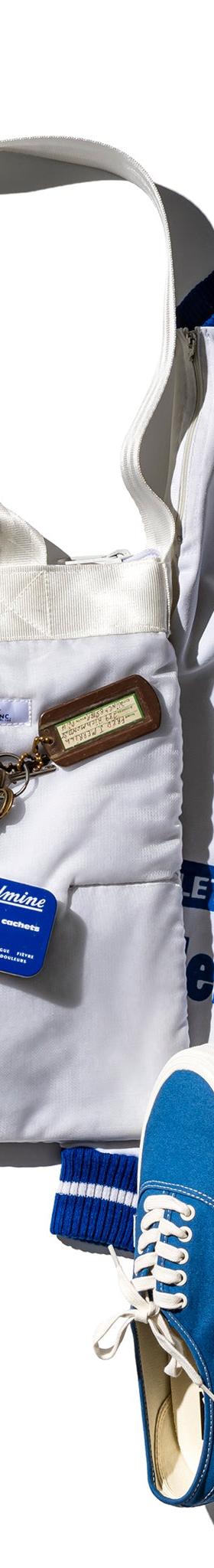 A white quilted Puebco tote bag styled with a blue track jacket and sneakers