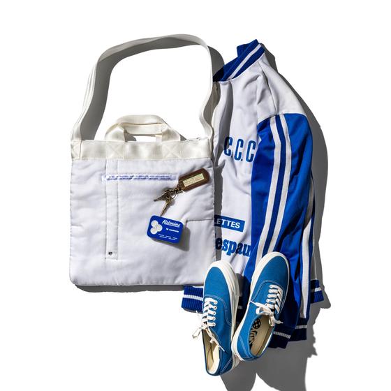 A white quilted Puebco tote bag styled with a blue track jacket and sneakers
