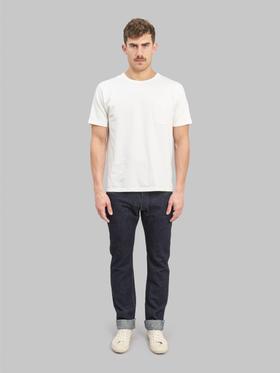 A man wearing a white pocket T-shirt with cuffed indigo Pure Blue Japan selvedge jeans