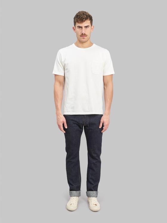 A man wearing a white pocket T-shirt with cuffed indigo Pure Blue Japan selvedge jeans