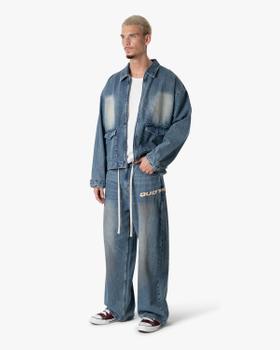 A man wearing a blue washed denim Quotrell jacket and wide-leg jeans