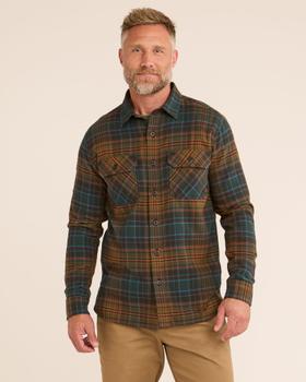 A man wearing a green and orange plaid Railcar Fine Goods flannel work shirt with tan trousers