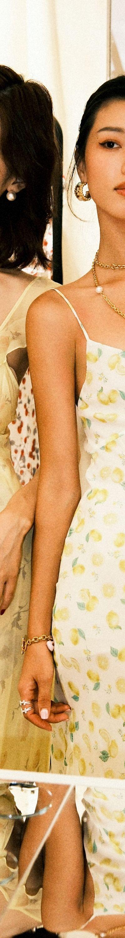 Two women wearing pastel yellow floral and lemon-print Realisation Par slip dresses in a boutique