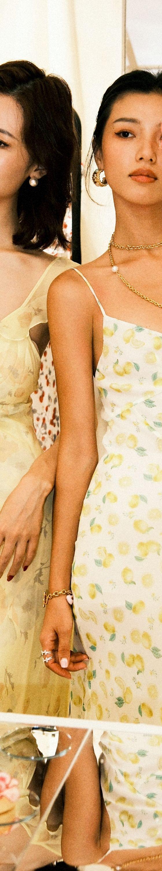 Two women wearing pastel yellow floral and lemon-print Realisation Par slip dresses in a boutique