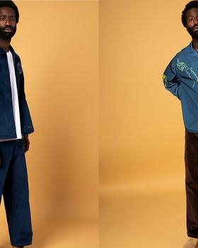 A man wearing a navy corduroy Reception jacket and matching trousers, and an embroidered teal camp-collar shirt