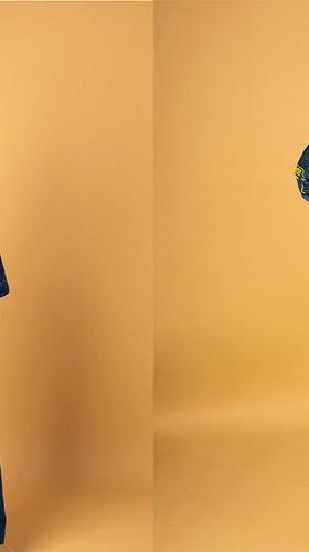 A man wearing a navy corduroy Reception jacket and matching trousers, and an embroidered teal camp-collar shirt