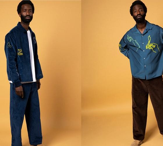 A man wearing a navy corduroy Reception jacket and matching trousers, and an embroidered teal camp-collar shirt