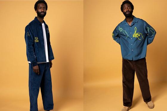 A man wearing a navy corduroy Reception jacket and matching trousers, and an embroidered teal camp-collar shirt