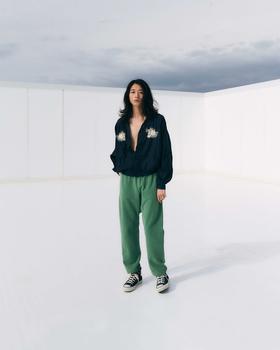 A woman wearing a navy REMI RELIEF pullover shirt with green sweatpants