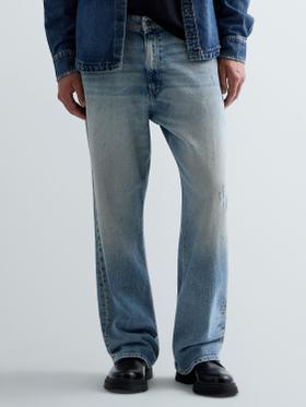 A man wearing light-wash Replay straight-leg jeans with a denim jacket