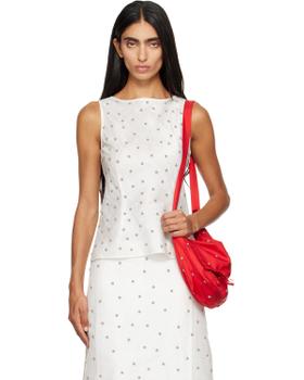 A woman wearing a white dotted RESCHA tank top and matching skirt with a red shoulder bag